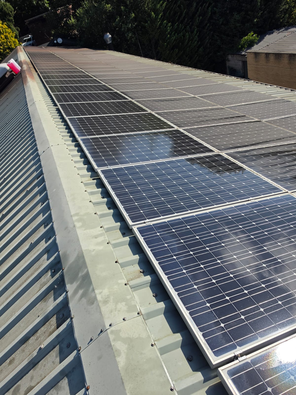 Freshly cleaned solar panels on a commercial roof, glass clear and reflecting the sky